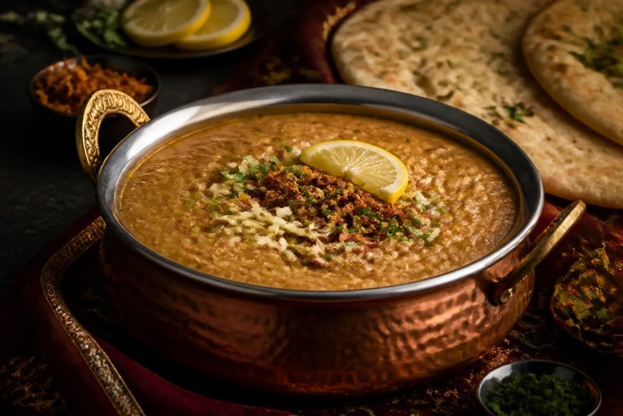 A pot of haleem served with lemon and fresh naan